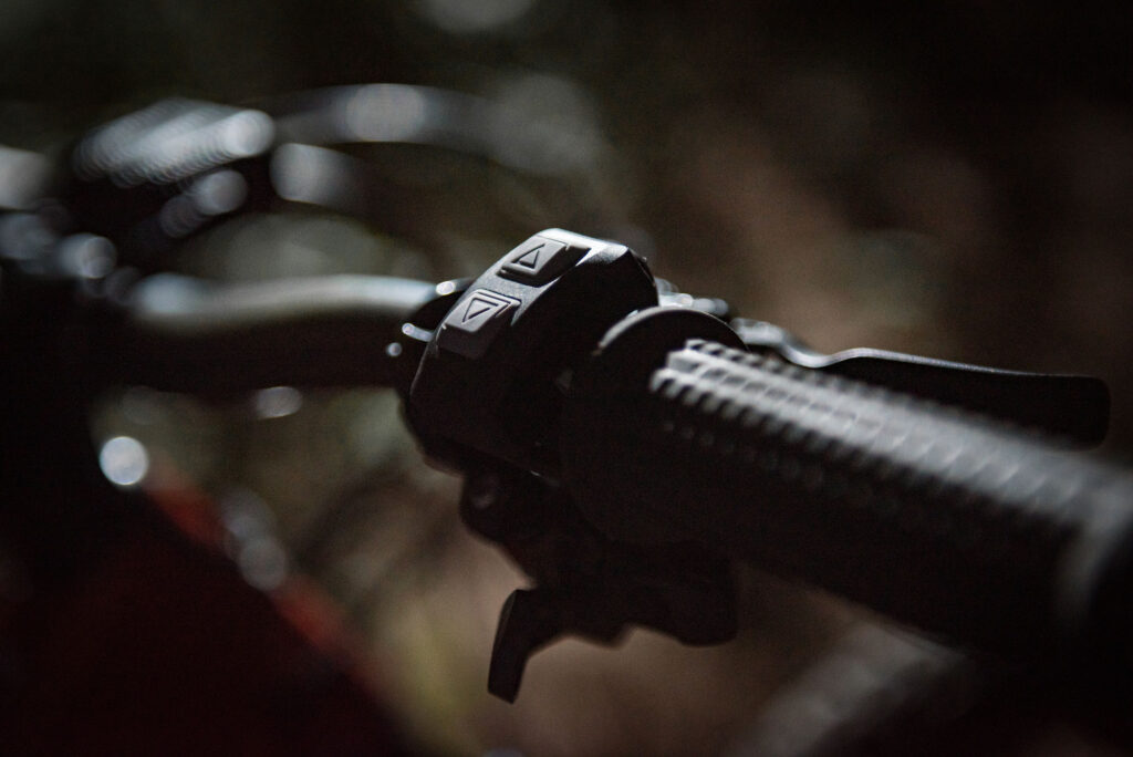 Close-up of Gloworm TX Wireless Remote mounted on mountain bike handlebars showing up and down arrow buttons for controlling bike light brightness.