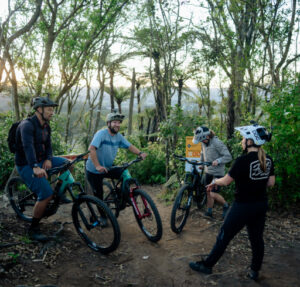 Videographer Paige Fensom discussing the shot list with riders Dave Armitage, Hannah Hamilton, and Nico Maybury during the Gloworm Lights production shoot in Rotorua.