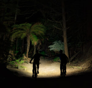 Nico Maybury and Dave Armitage riding through Whakarewarewa Forest at night with Gloworm Lights G2.1 Series, celebrating the wrap of the production shoot after completing the final shot.